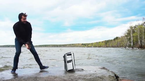Man Destroying Old Desktop Computer with Sledgehammer By the Lake