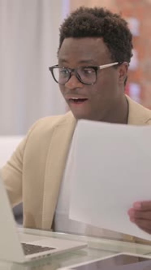 Man Celebrating Success Looking at Laptop and Documents