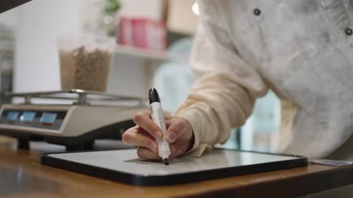 Woman Writes on the Blackboard with Marker the Weight of the Goods in Her Container in the Store