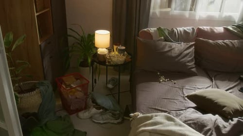 No People Shot of Unmade Bed and Side Table with Snacks in Messy Bedroom