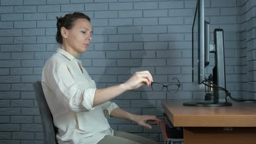 Woman Applies Cotton Rounds to Eyes at Desk