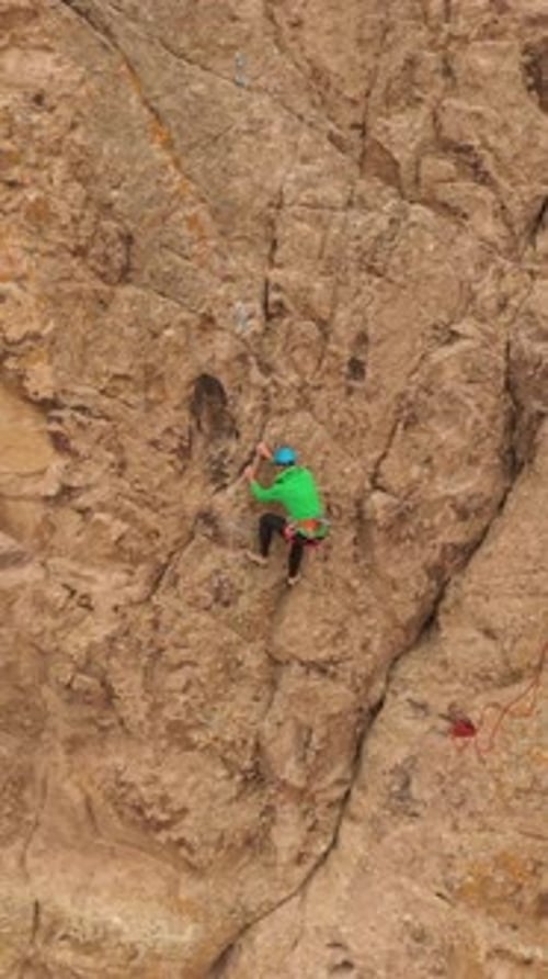 Man Climber Rock Climbing Cliffs in Tamgaly Tas Kazakhstan Aerial View Vertical Video