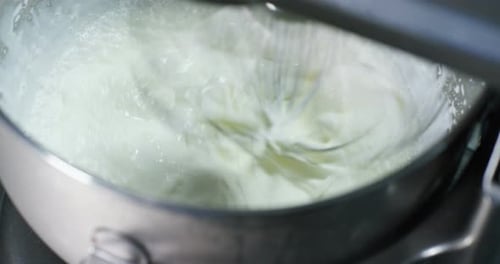 Tasty white cream stirs machine at professional factory making sweets, on white background. Concep