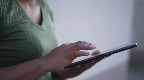 Nahaufnahme weiblicher Hände, die ein Tablet-Gerät halten und den Bildschirm mit dem Finger im Freien berühren