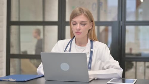 Smiling Woman Doctor Using Laptop Computer in Office