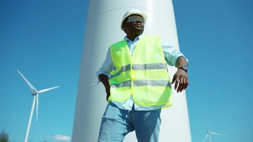 Smiling African American Man Engineer in Uniform Stand Near Wind Turbines Ecological Energy Industry