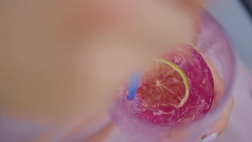 Hand of a Young Woman Stirring a Cocktail in a Glass with a Straw Closeup Shot