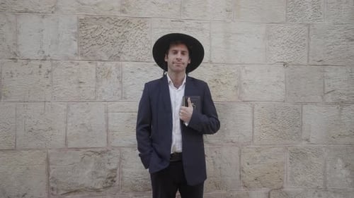 Homme juif orthodoxe debout devant un mur de pierre