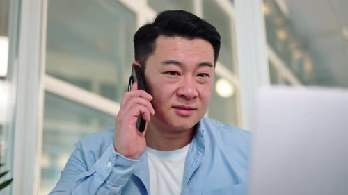 Portrait of Asian Businessman Discussing Good News on Phone During Workday