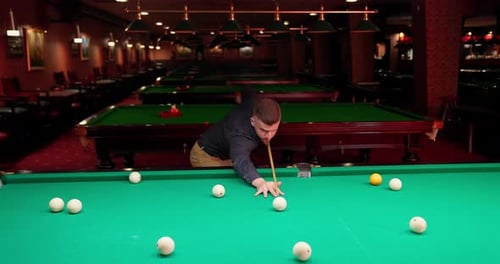 Man Playing Pool in a Darkly Lit Room