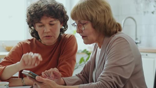 Women Collaborating on Smartphone in Bright Kitchen