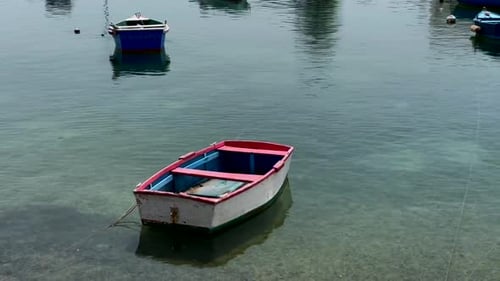 This video shows a small boat floating on a serene lake in a quaint village. The water is calm and r