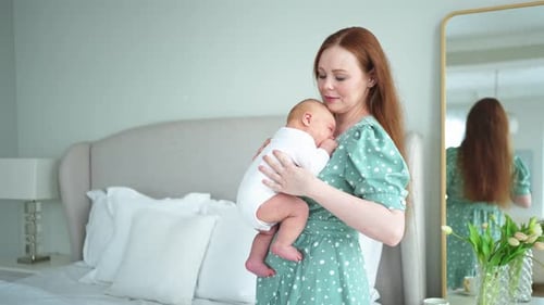 Mother Holding Newborn Baby in Bedroom