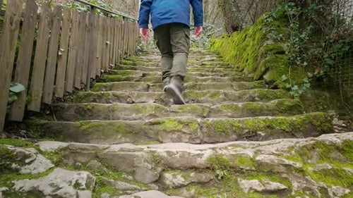 Active senior man ascends a steep flight of old uneven stone steps outdoors