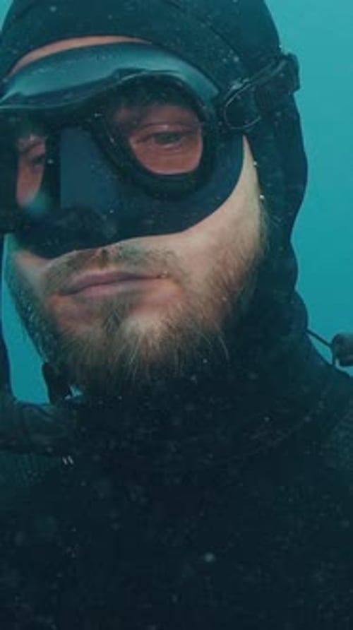 Close up portrait of the relaxed male freediver ascending along the rope during free diving
