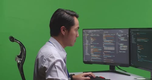 Close Up Of Asian Man Developer Using Computer To Write Code With Multiple Screens In Green Screen