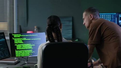 Junger männlicher Programmierer überprüft den Tippfortschritt seiner jüngeren Kollegin