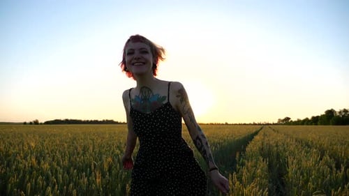 Happy Punk Woman with Tattoos Jogging Through Wheat Meadow at Beautiful Sunset Joyful Female Hipster