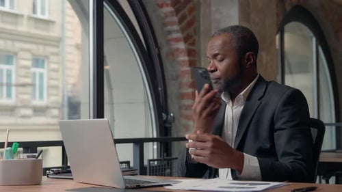 Focused Businessman Talking on Phone While Using Laptop