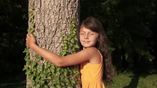Criança sorridente abraça árvore solitária.