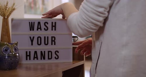 Woman walks in and Switches on Decorative Lightbox Written Wash Your Hands in Comfy and Cozy Home