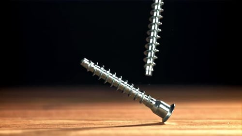 Screws Falling onto a Wooden Surface, Close Up