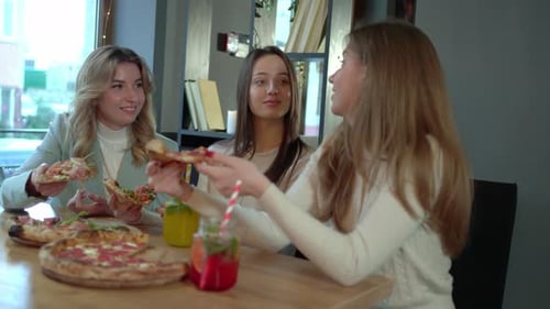 Frauen essen zusammen Pizza am Tisch in der Cafeteria