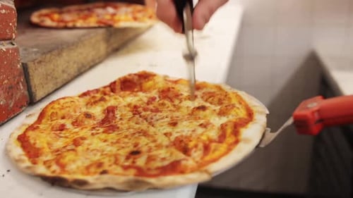 Concepto de comida, cocina italiana y cocina: cocina con un cortador para cortar pizza