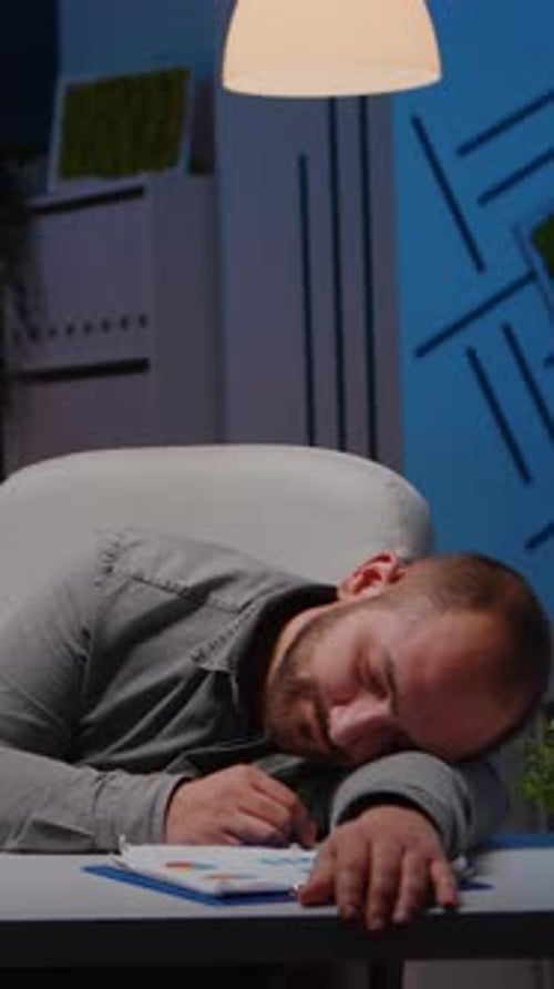 Exhausted Overworked Businessman Sleeping on Desk Table in Startup Business Office