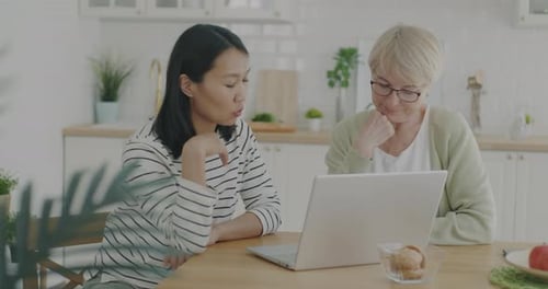 Young Woman Helping Senior Woman Use Laptop