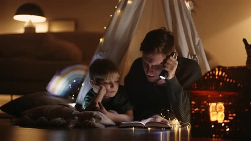 Adult and Child Reading with Flashlight at Night