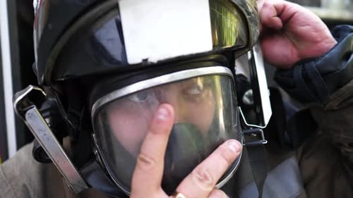 Firefighter Adjusts Helmet Near Firetruck, Close Up