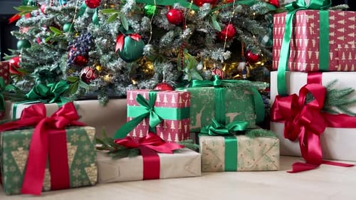 Close up of gift boxes on the background of a Christmas tree. Red and green Xmas gifts lying under