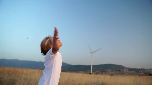 Boy Stands with Arms Outstretched in Rural Field