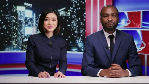 News Anchors Presenting in Modern Broadcast Studio