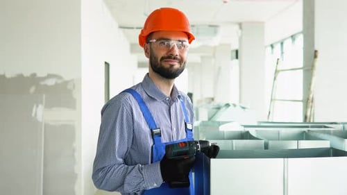 Construction Worker Holding a Drill Indoors