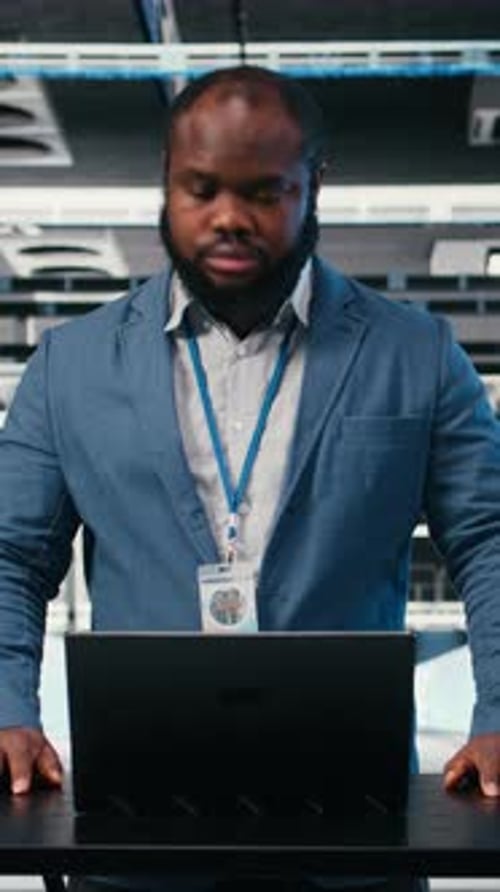 Vertical Video Server Farm Programmer at Workplace Desk Using Laptop to Optimize Electronics