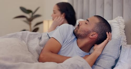 Man Lying Awake Next to Woman in Bed