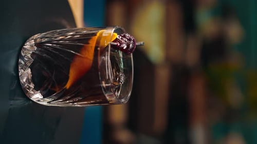 vertical video freshly prepared black alcoholic cocktail rotates on the bar counter in the bar-club