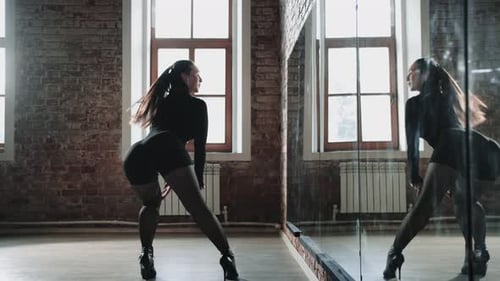 Attractive Woman Dancer Practicing in the Studio in Front of a Mirror