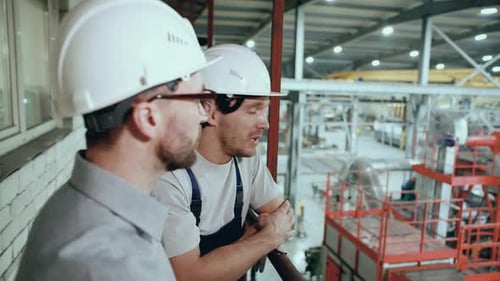 Engineer Supervising and Discussing Factory Operations with Worker