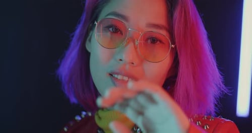 Closeup Portrait of Carefree Asian Student Dancing Moving Hands in Neon Illuminated Night Club