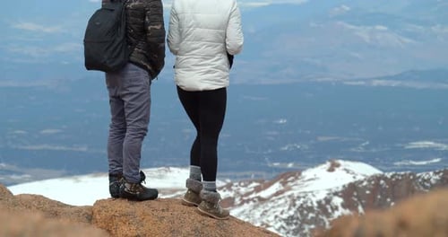 Couple reaching rocky mountains summit in Colorado wilderness on a sunny day