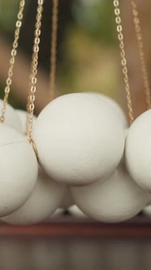 White Balls Suspended on Chains Above Wooden Playing Field