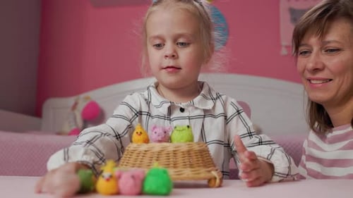 Mädchen, Kind und Mutter spielen mit kleinen gestrickten Tierspielzeugen in einem Zimmer zu Hause