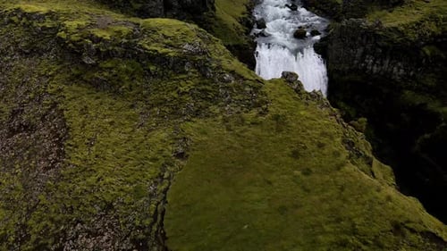 Großer Wasserfall, versteckt in der Mitte der Berge in der Nähe von Skogafoss in Island. Drehen Sie sich aus der Luft