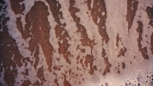 Close up of small ocean waves gently rolling onto the sandy beach at sunset