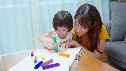 Child Drawing with Crayons with Adult Supervision