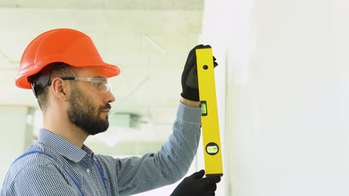 Construction Worker Using a Level on White Wall