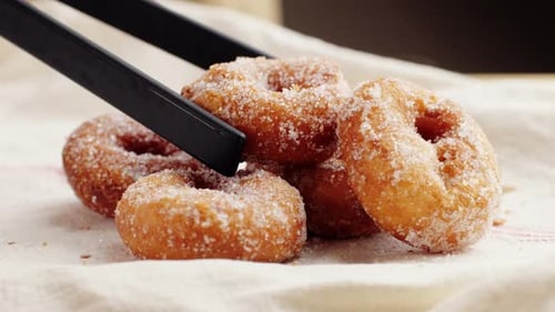 Traditionelle spanische Donuts mit bunten Streuseln, Nahaufnahme von rosafarbenen Süßigkeiten, Lebensmittelmakro